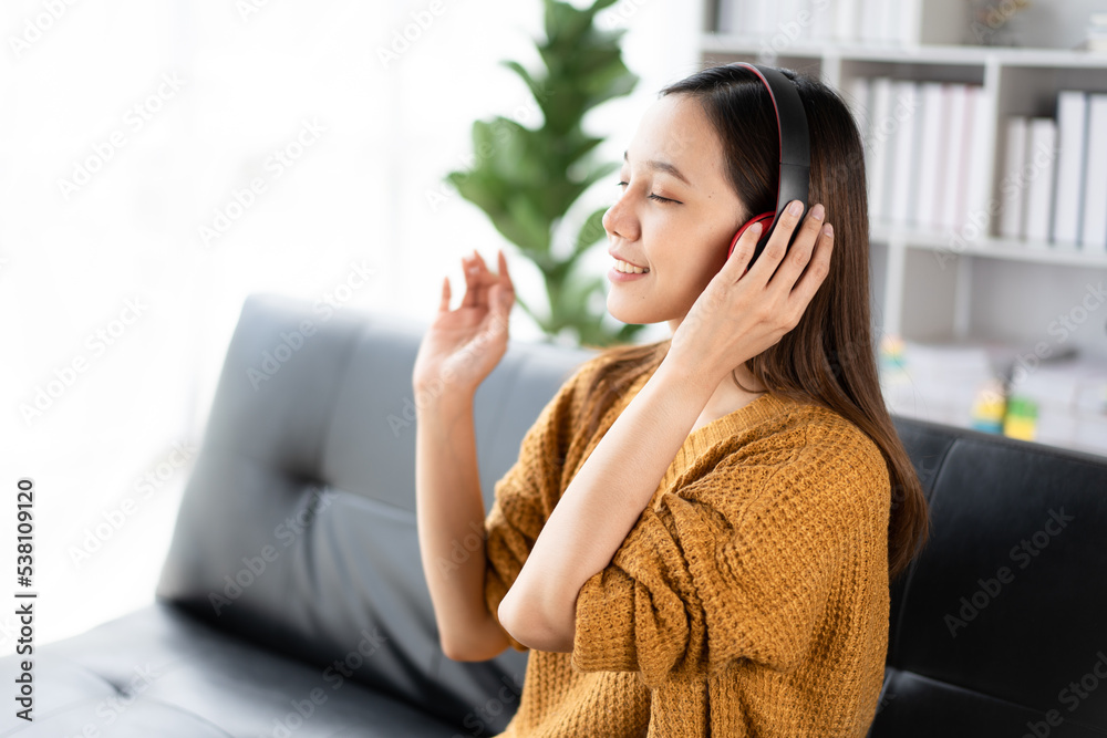 一位快乐的年轻亚洲女性用音乐应用程序的无线耳机听音乐的肖像