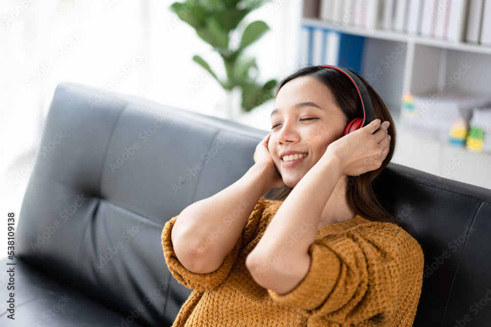 一位快乐的年轻亚洲女性用音乐应用程序的无线耳机听音乐的肖像