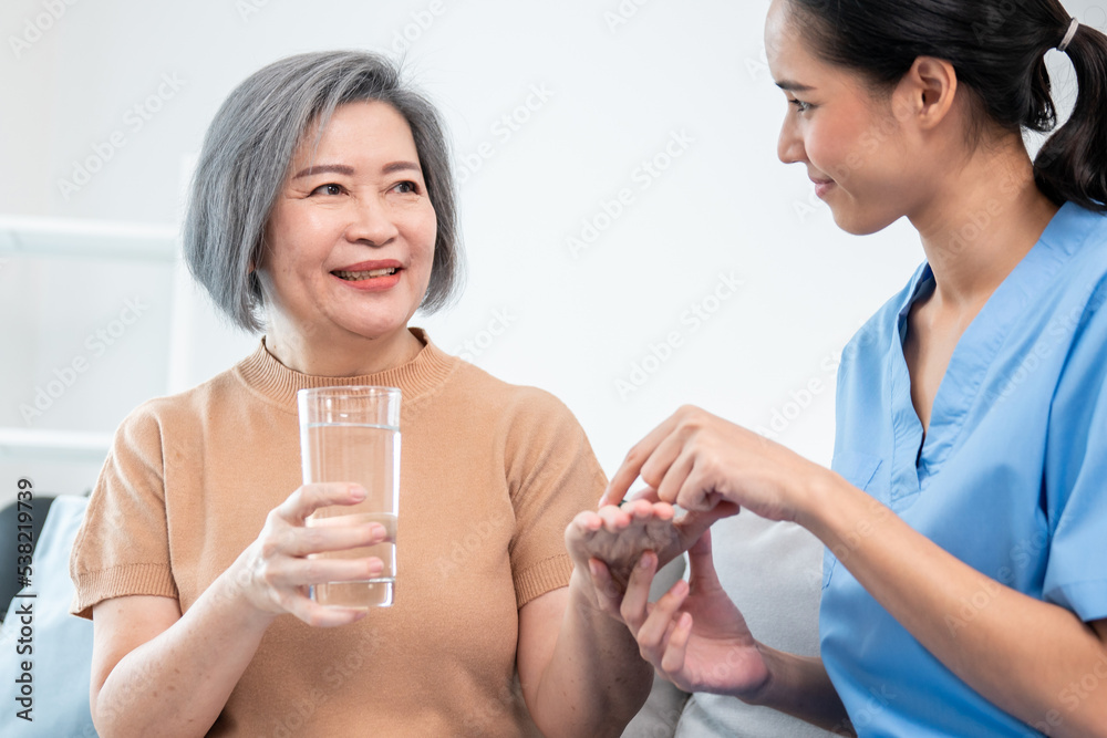 Contented senior woman taking medicines while her caregiver advising her medication. Medication for 