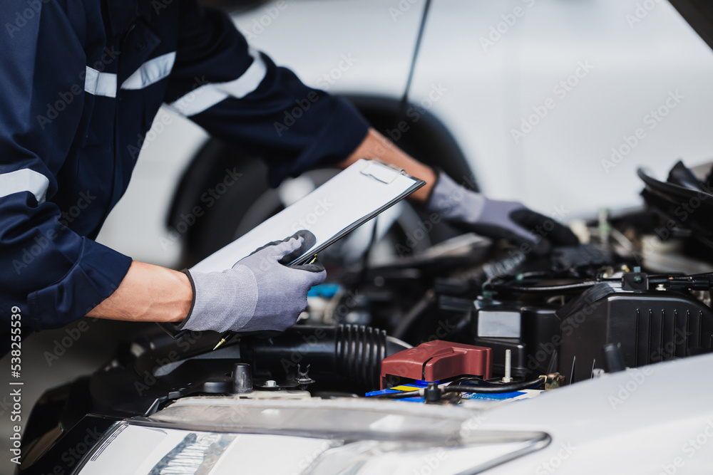 Professional mechanic working on the engine of the car in the garage. Car repair service.