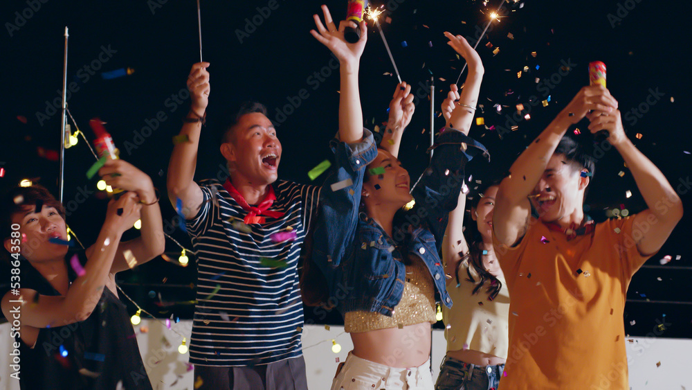 Group of young Asian people with friends celebrating party on rooftop holding sparklers fireworks an