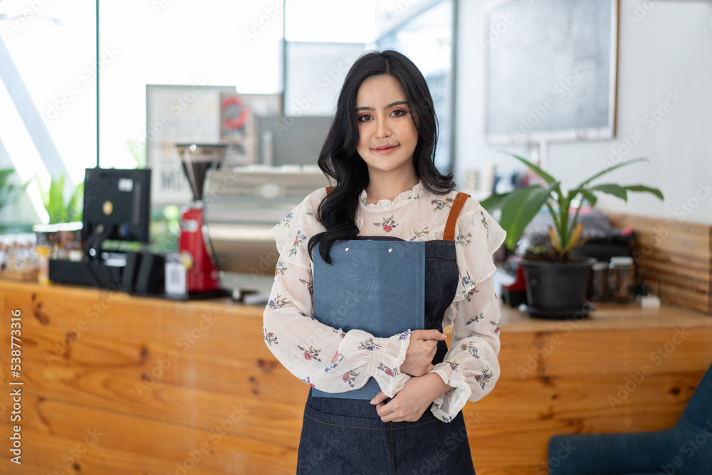 Happy Asian woman in an apron standing near a bar counter coffee shop, Small business owner, restaur