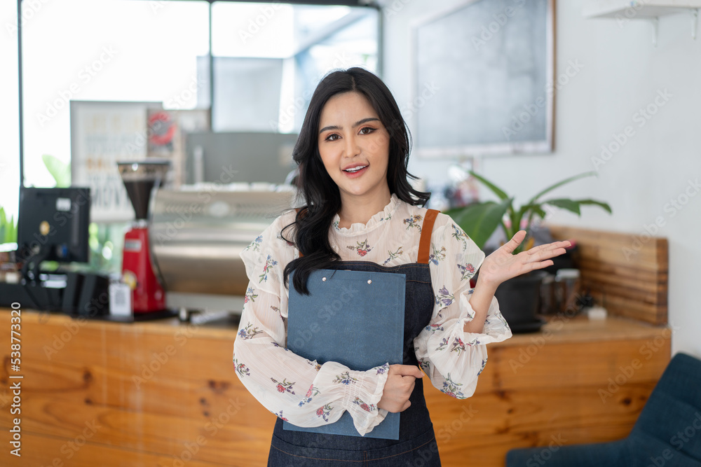 Happy Asian woman in an apron standing near a bar counter coffee shop, Small business owner, restaur