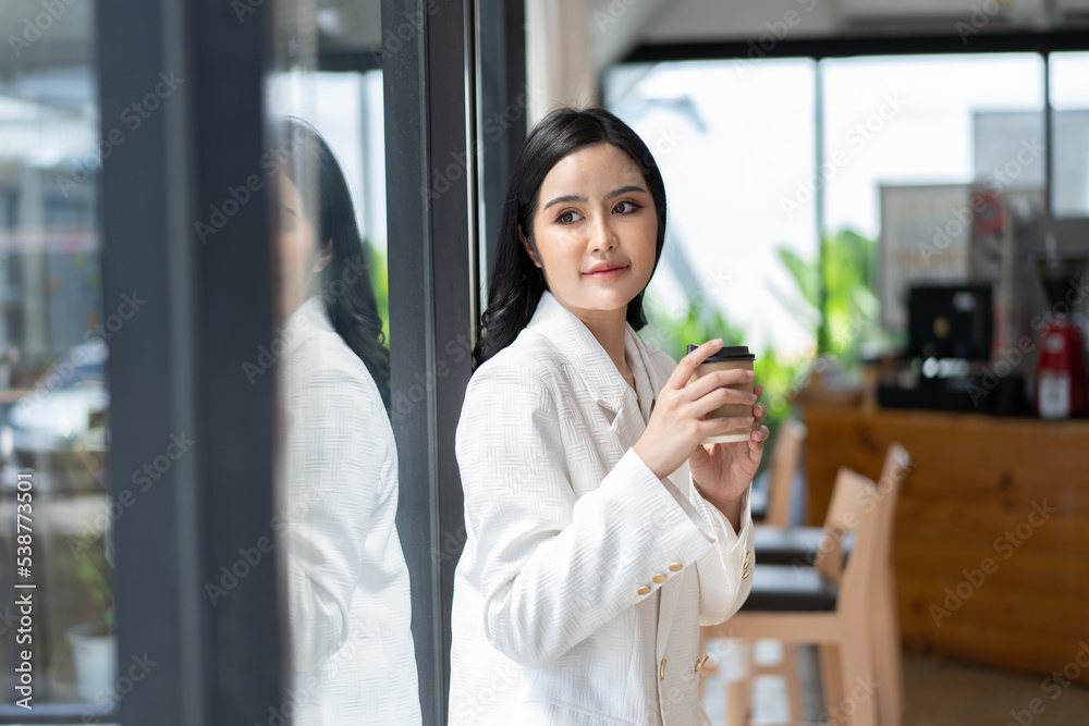 快乐的亚洲年轻女子在咖啡馆喝咖啡。