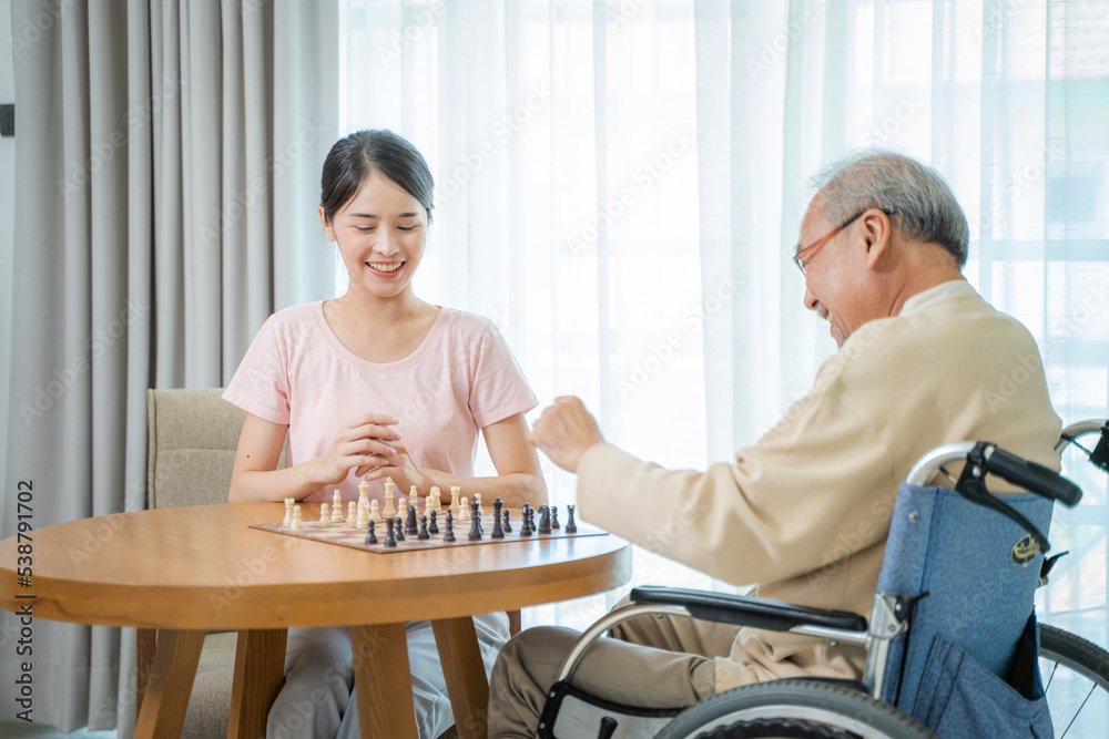 快乐老人坐在轮椅上和女儿在家下棋，玩野猪