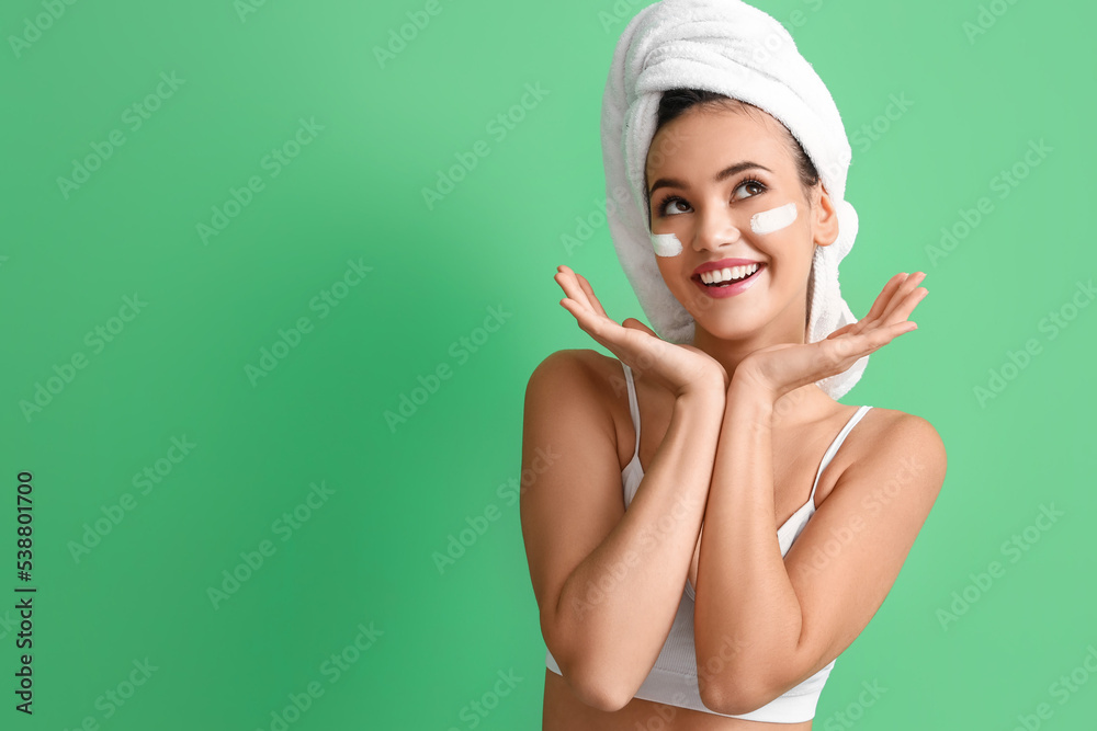 Beautiful young woman with facial mask on green background