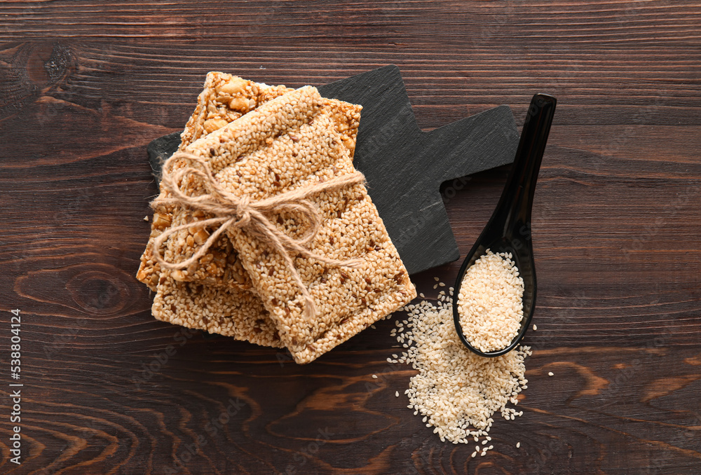 Board of tasty kozinaki bars with sesame seeds on dark wooden background