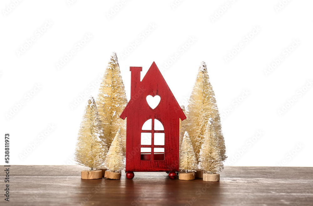 House figure with Christmas trees on table against white background