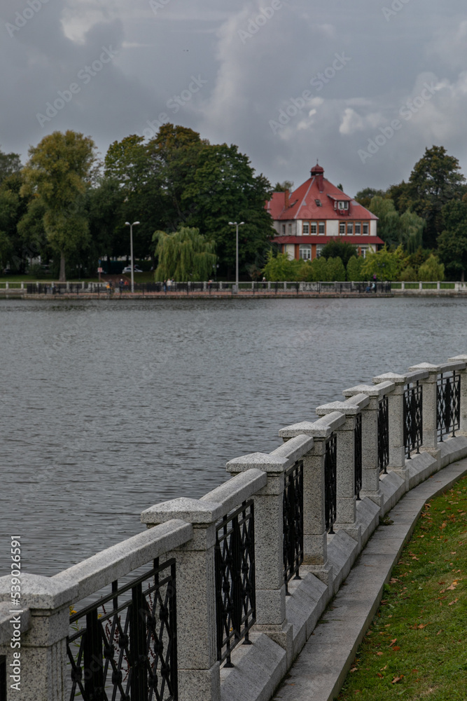 City embankment of Upper Pond in Kaliningrad in the cloudy day. Curly white stone and metal fence al