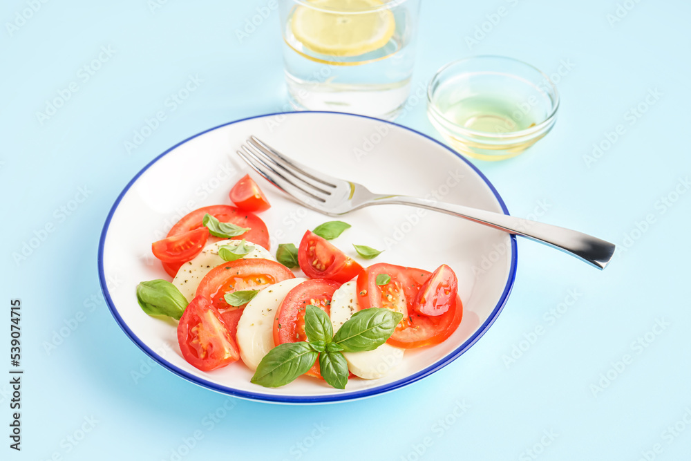 Plate of tasty caprese salad on color background