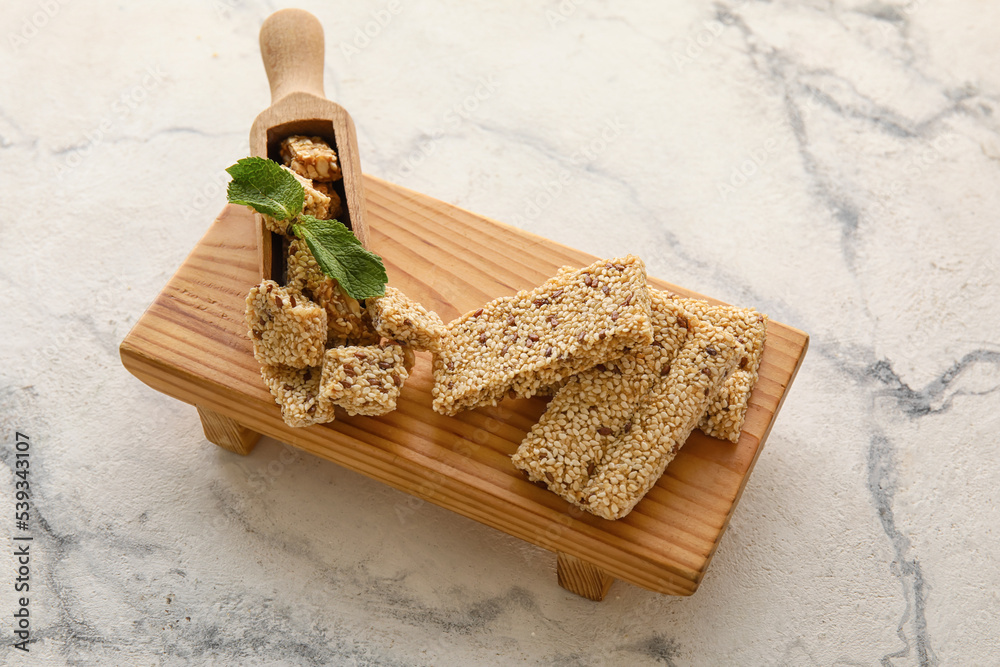 Wooden board with tasty sesame kozinaki on light background