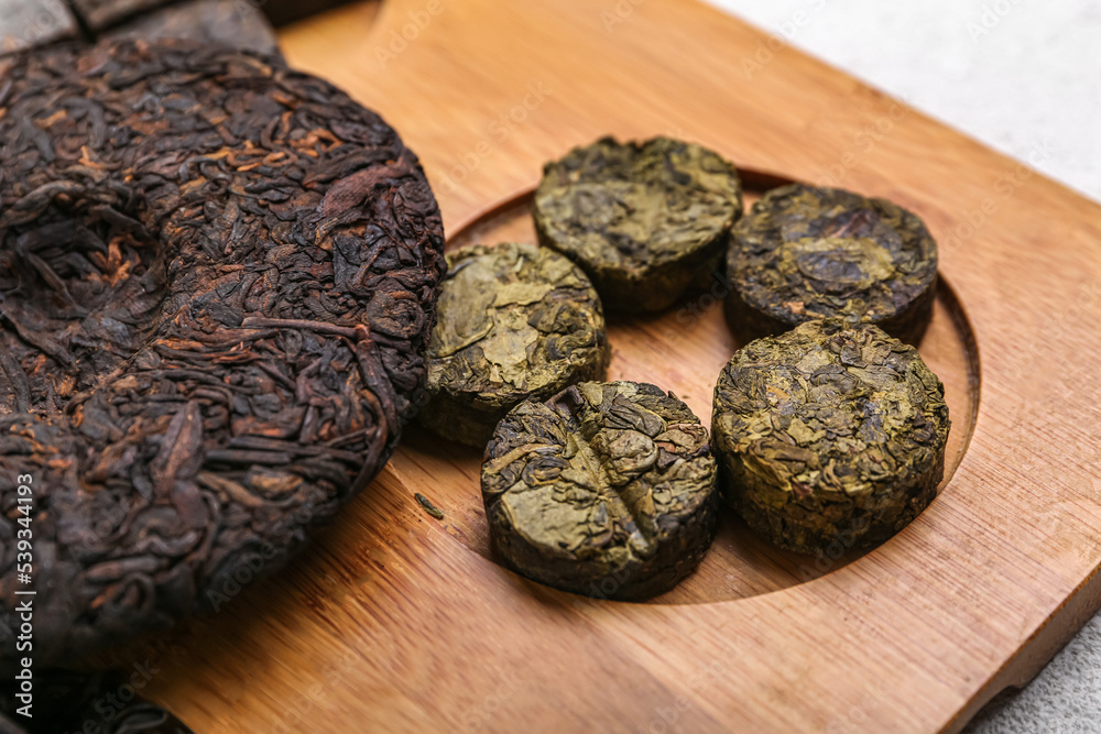 Board with dry pressed puer tea on white background, closeup