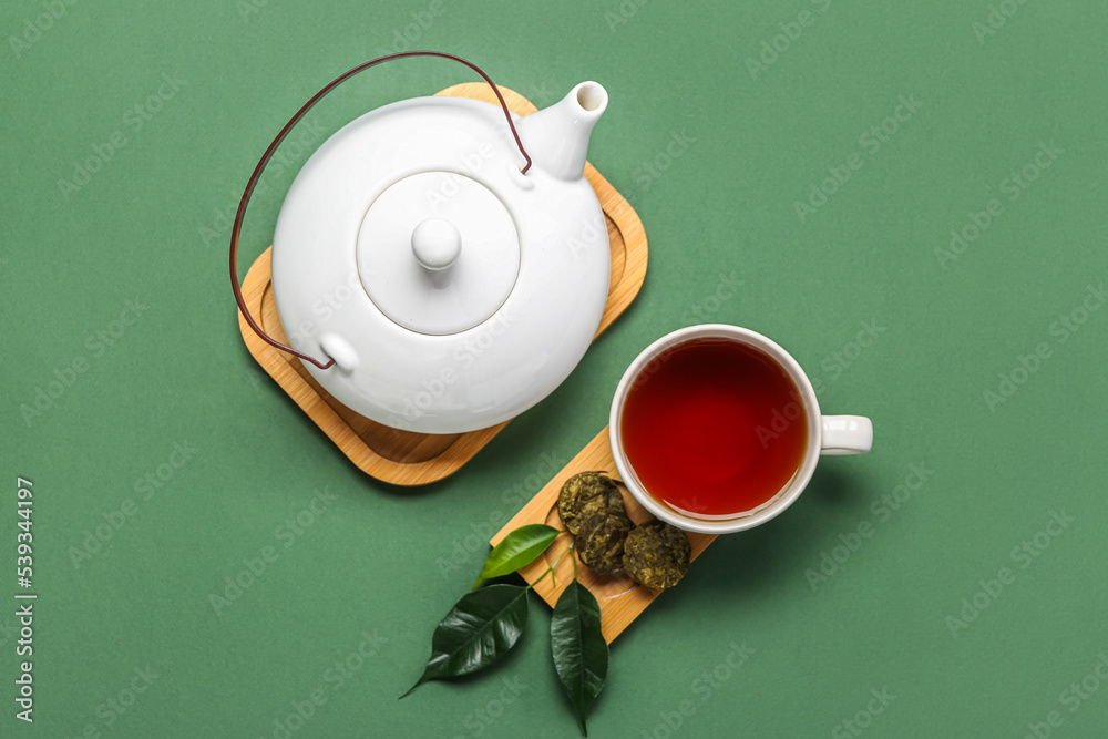 绿色背景上有干压普洱茶、杯子和茶壶的木板