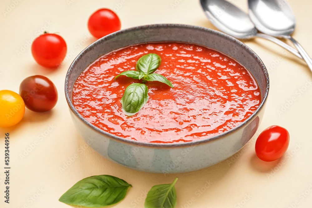 Bowl of delicious tomato soup on color background, closeup