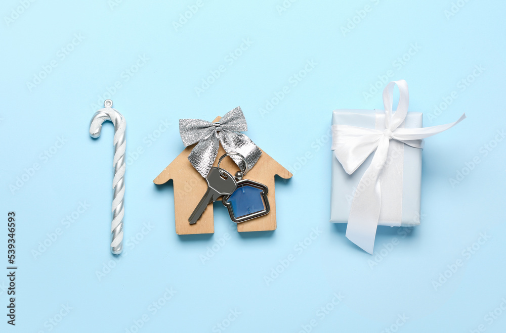 House figure with key, Christmas gift and candy cane on blue background