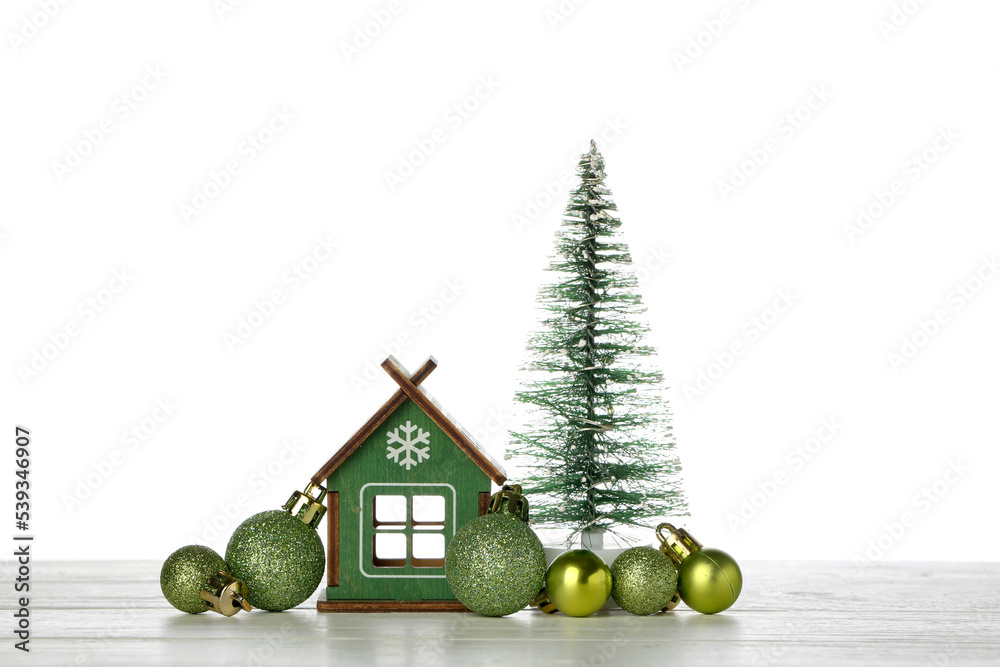 House figure with Christmas tree and balls on table against white background