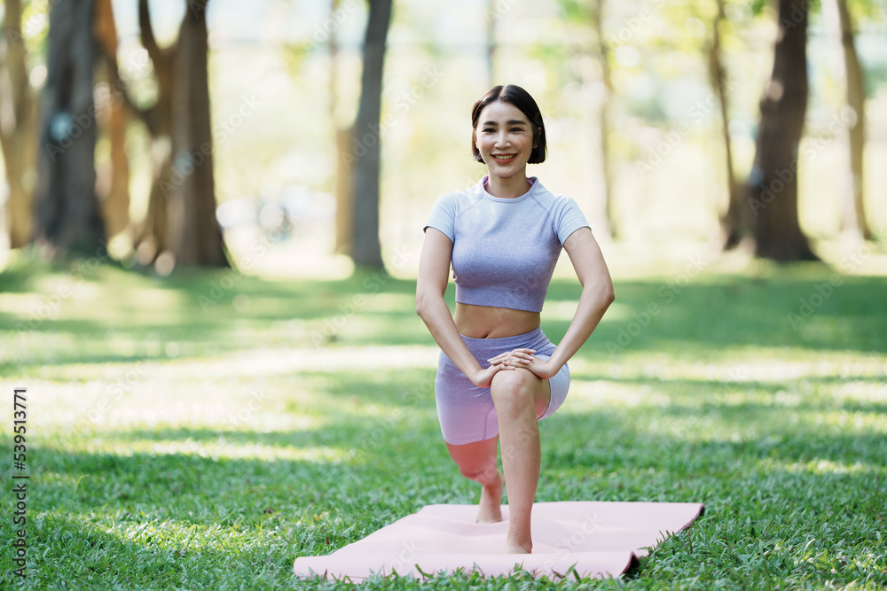 美丽的年轻亚洲女性在公园里练习瑜伽。