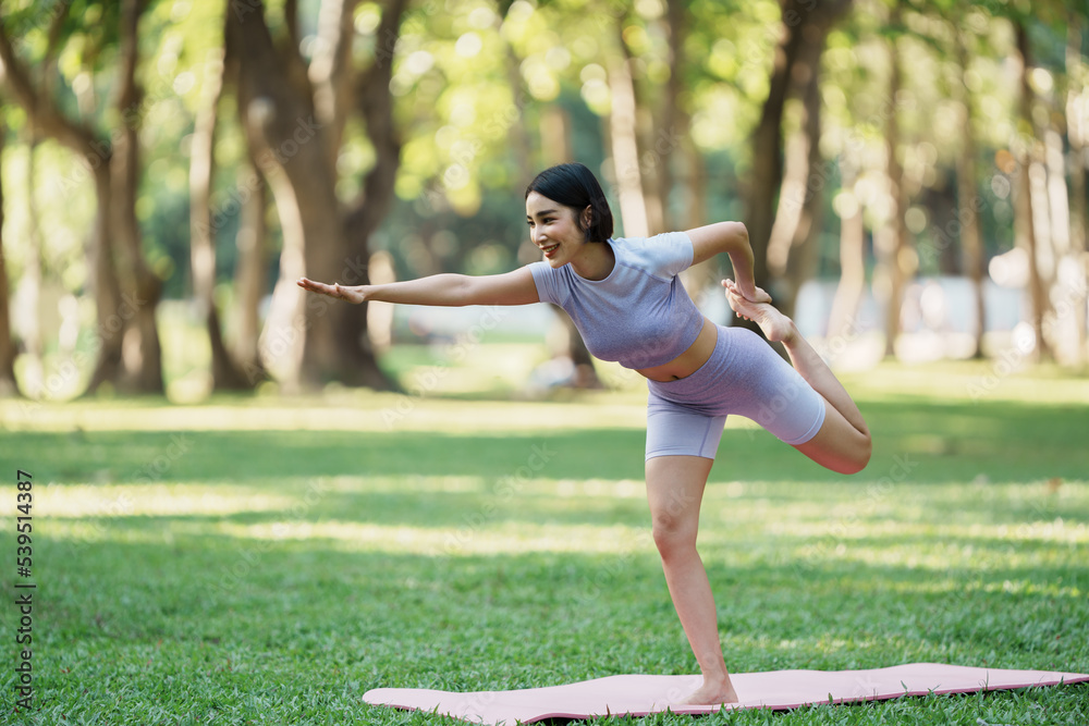 Beautiful young asian woman yoga exercising in the park.