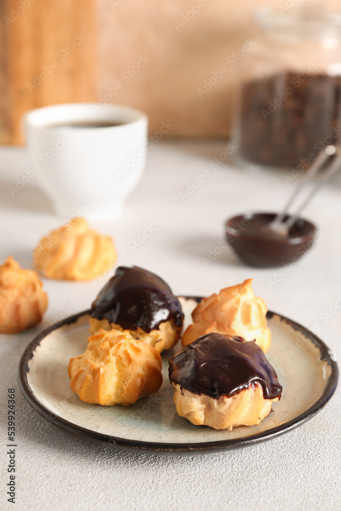 Plate with tasty eclairs on table