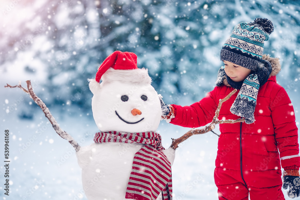 一个微笑的小孩正在堆一个可爱的雪人。