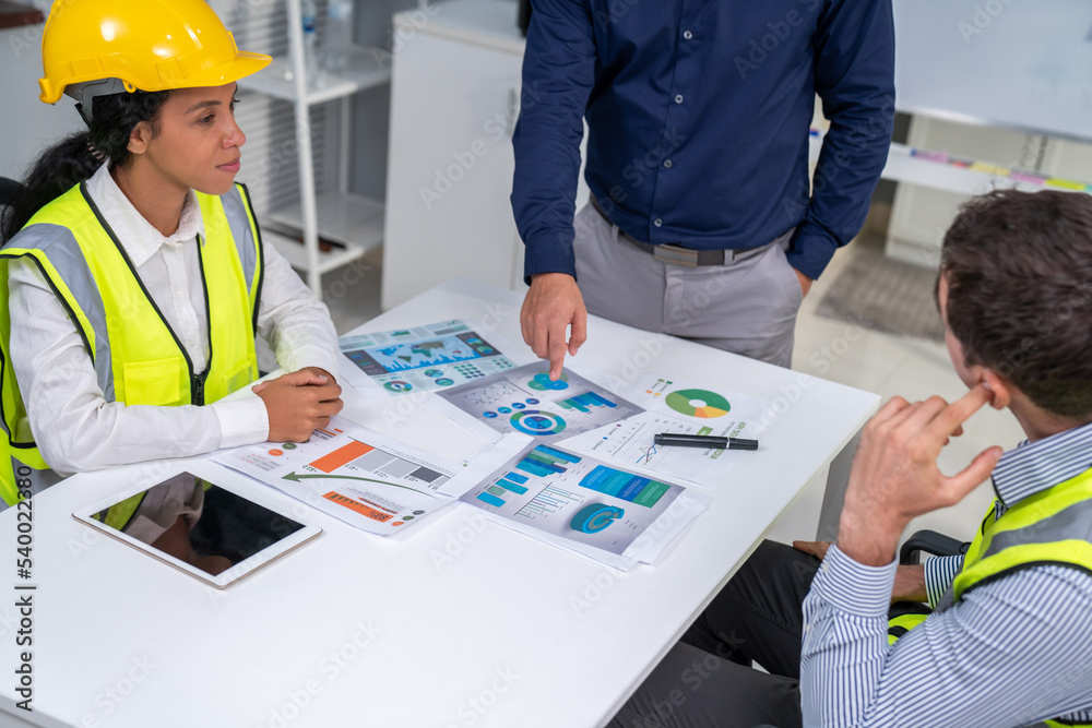 Engineers and competent employer discussing plans and blueprints together with tablet in the office.