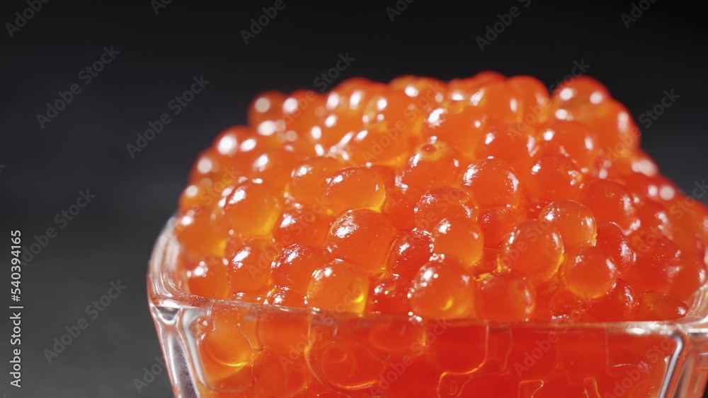 Red Caviar rotated over black background. Close-up salmon caviar rotation.