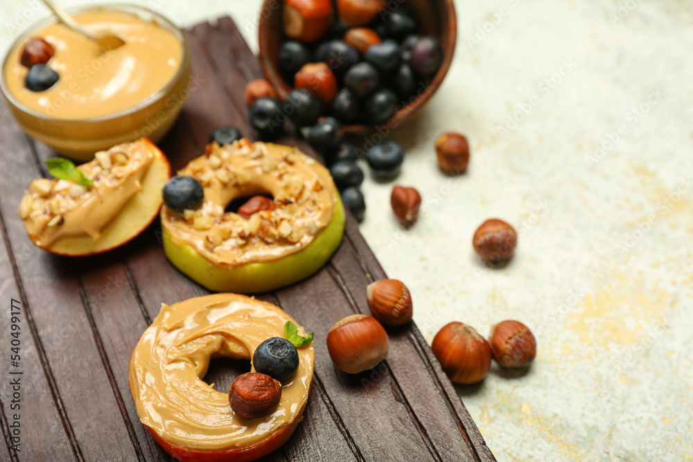 Wooden board of fresh apples with nut butter on light background, closeup