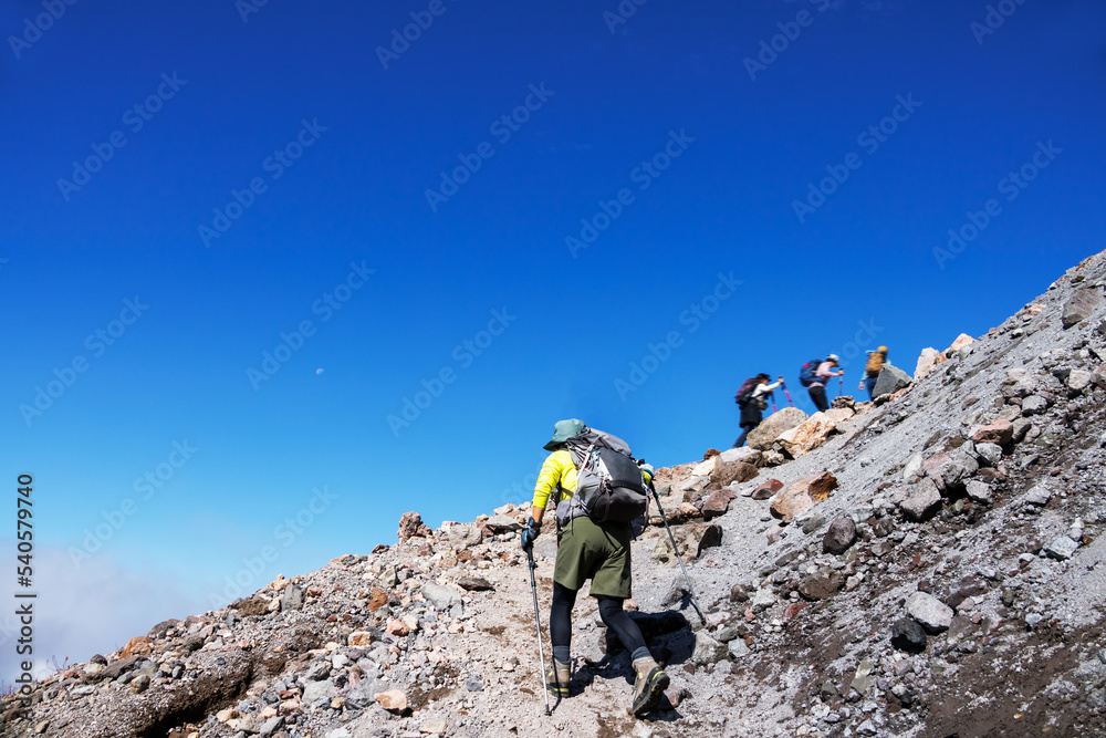 青空と雲と石だらけの登山道