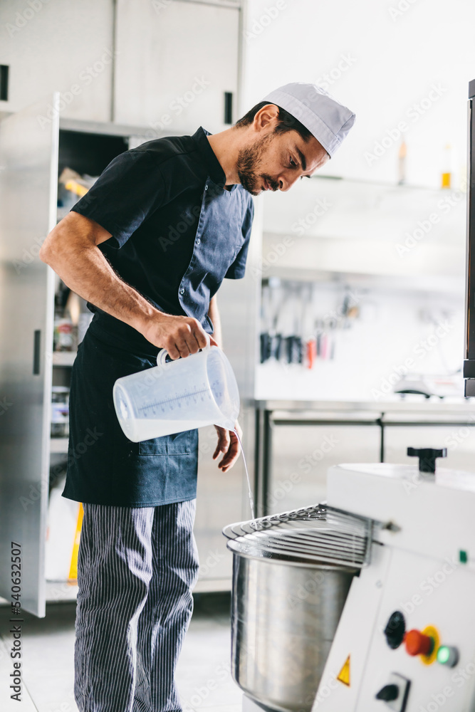 Italian chef pizzaiolo preparing pizza dough in restaurant kitchen