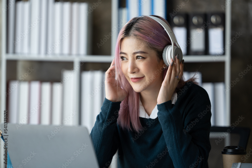 一位年轻的女学生坐在桌子旁，学习时使用耳机。