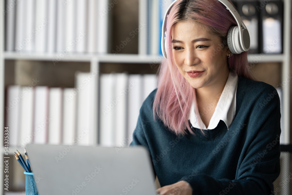 一位年轻的女学生坐在桌子旁，学习时使用耳机。