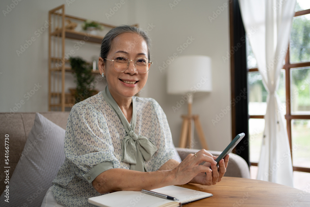 在家里使用智能手机的休闲和人的概念——快乐微笑的老年女性。