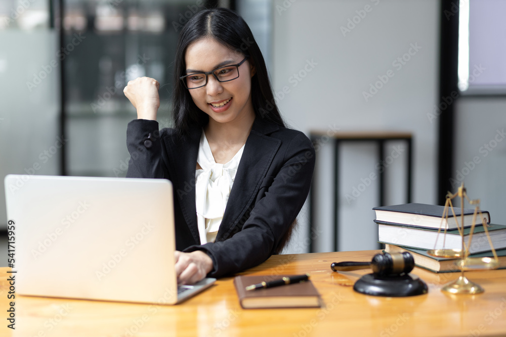 在律师事务所使用笔记本电脑的女律师。