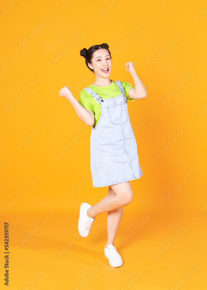 Full length image of young Asian woman standing on background