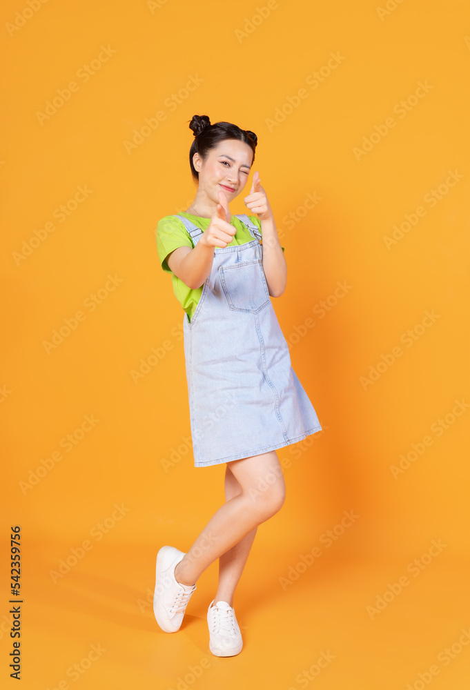 Full length image of young Asian woman standing on background