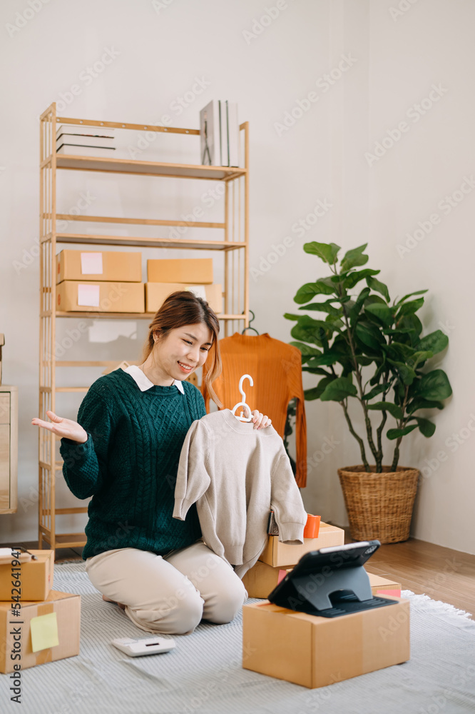 Portrait of Asian young woman SME working using smartphone or tablet taking receive and checking onl