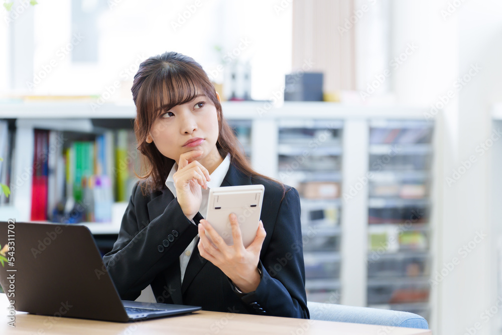 電卓を持って考える女性