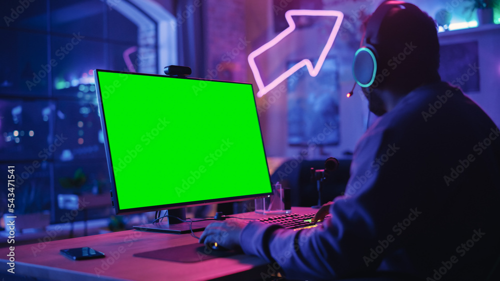 Excited Gamer Playing Online Video Game with a Mock Up Green Screen on His Powerful Personal Gaming 