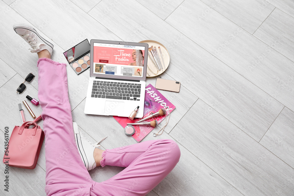 Female beauty blogger with laptop, decorative cosmetics and accessories on light wooden floor