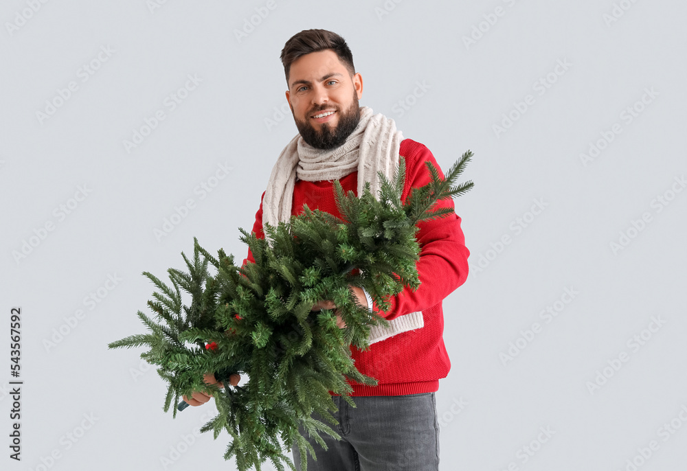 Handsome man with Christmas tree on grey background