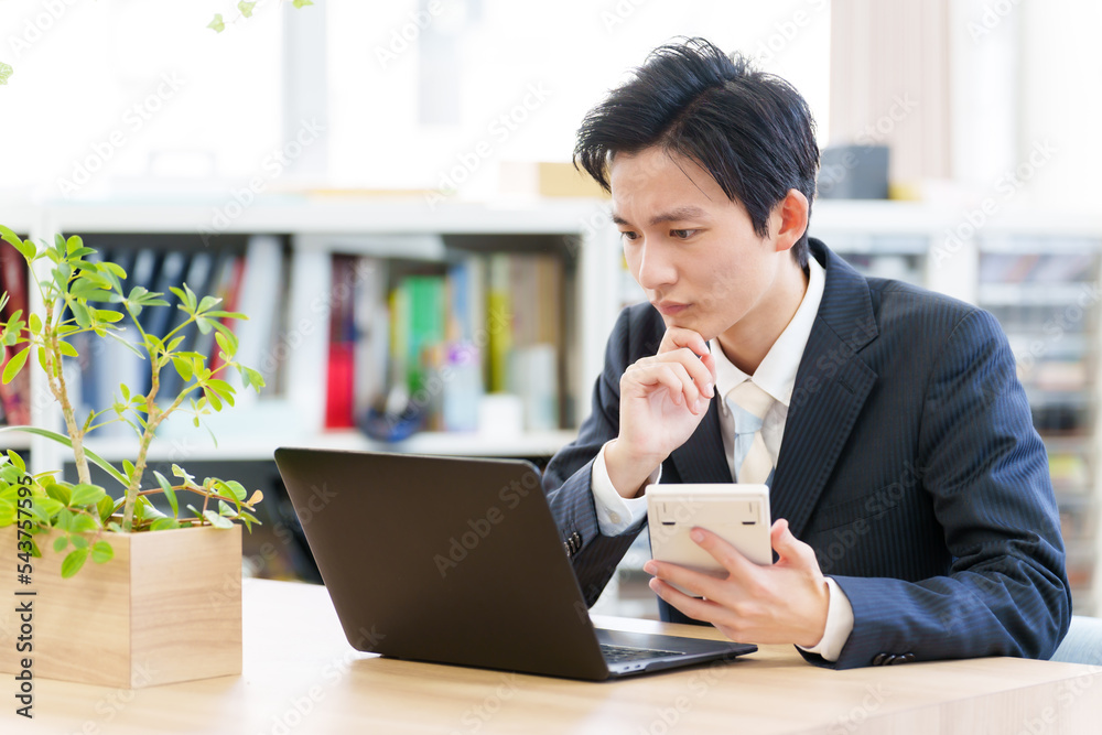 電卓を見ながら悩む税理士