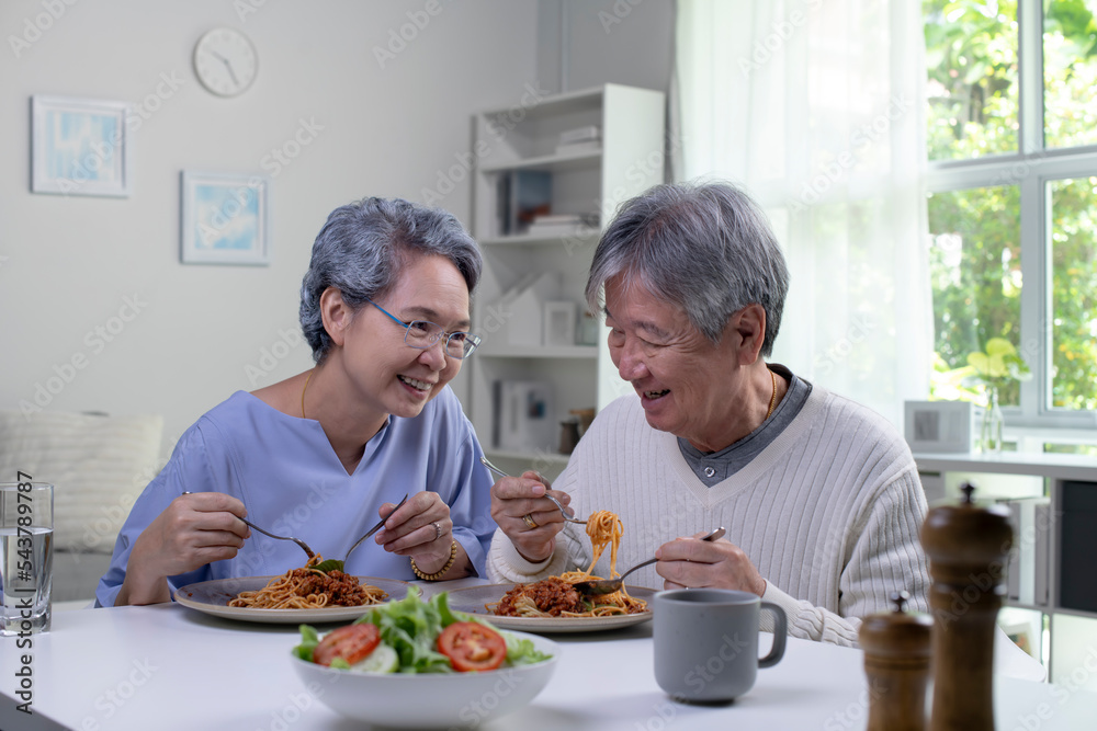 幸福的亚洲老年夫妇在家里的厨房里一起吃饭。退休老年夫妇生活方式