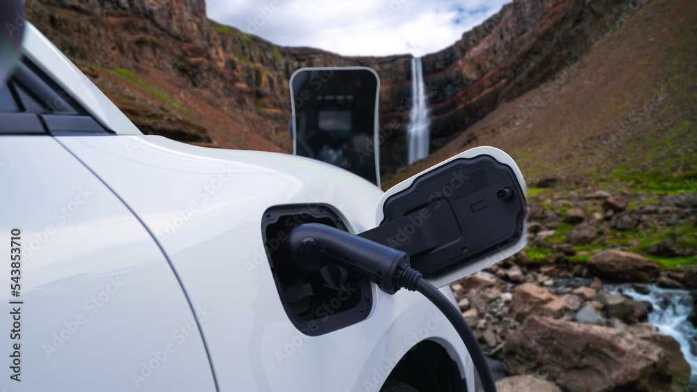 Electric car charging energy from charging station in the natural scenery, waterfall and stream back