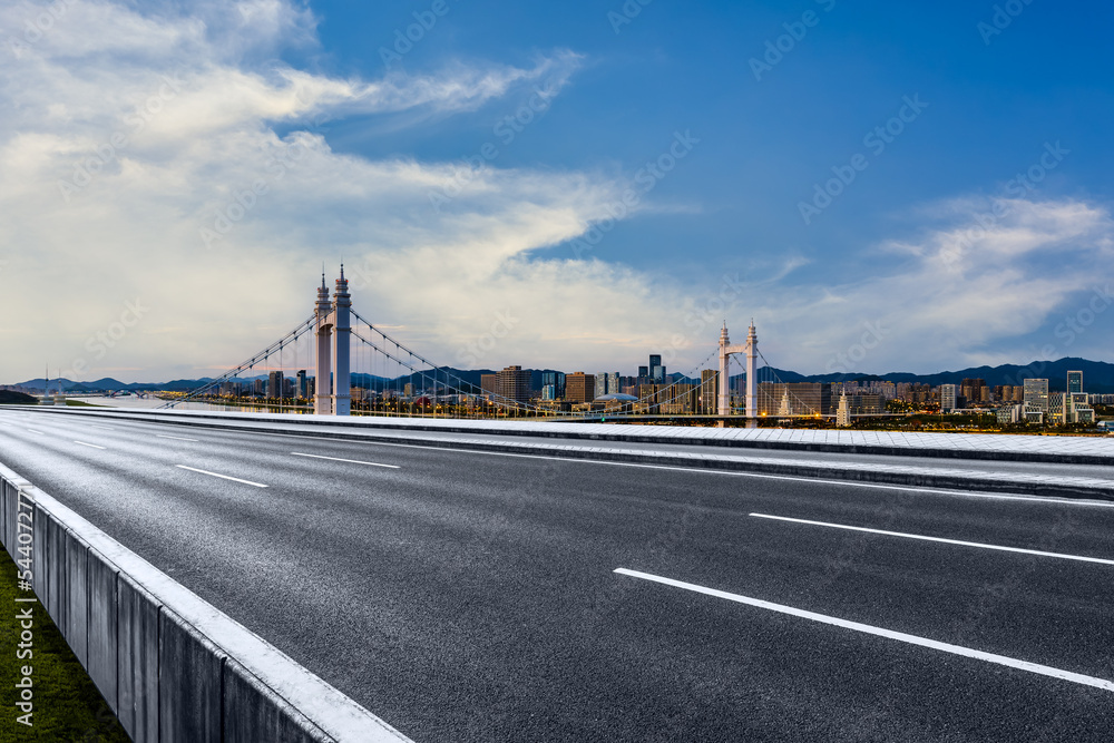 Asphalt road and bridge with city skyline at sunset in Zhoushan, Zhejiang, China.