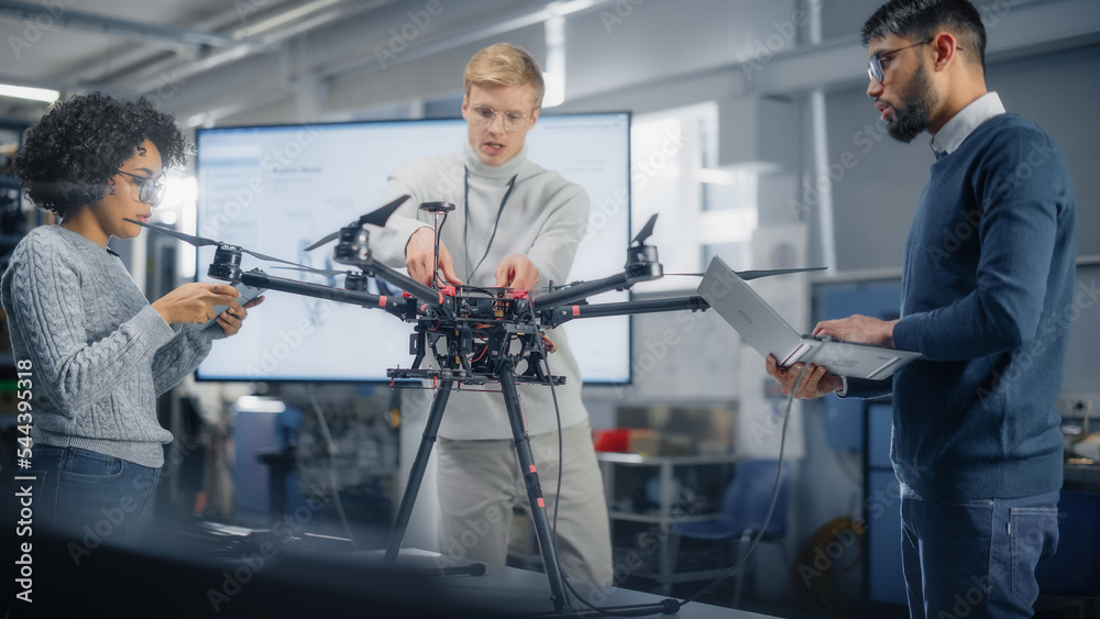 Black Male Engineer Coding on Laptop While Programming Drone with his Colleagues In the Factory Labo