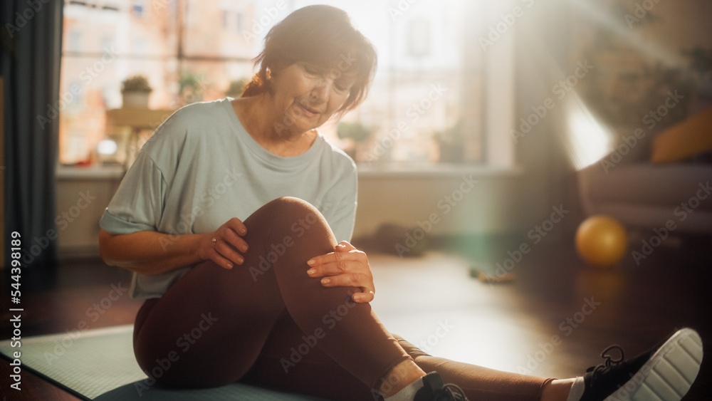 老年女性在晨练时在瑜伽垫上锻炼时感到不舒服的膝盖疼痛