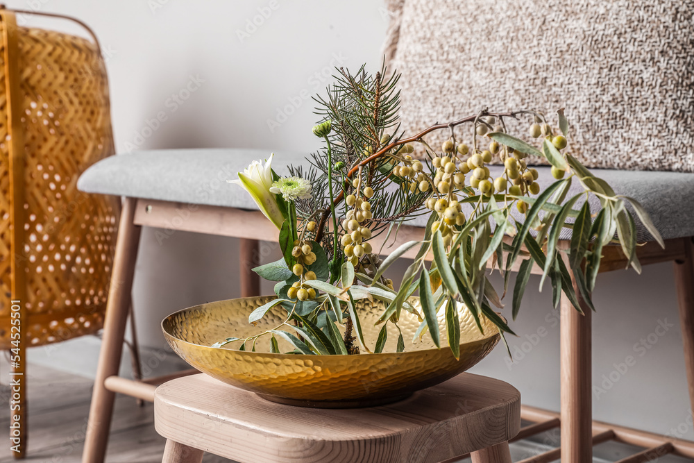 Bowl with beautiful ikebana on stool in light room, closeup