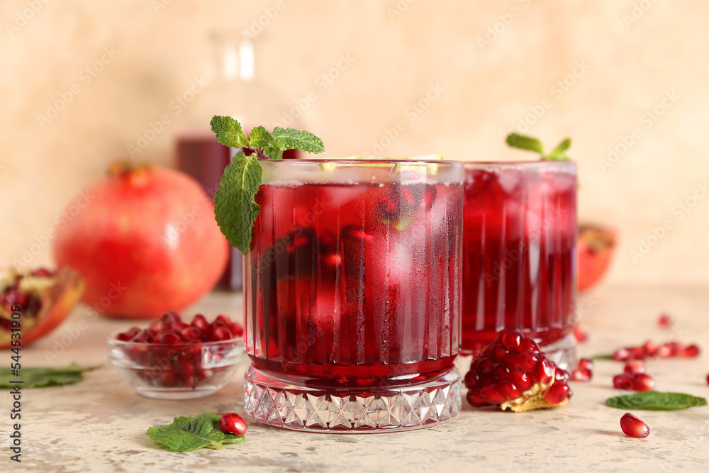 Glasses of cold pomegranate juice on color background