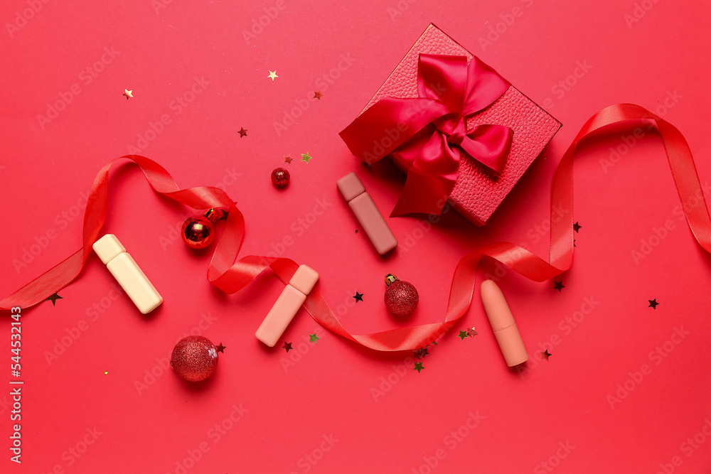 Lipsticks with Christmas decor and gift on red background