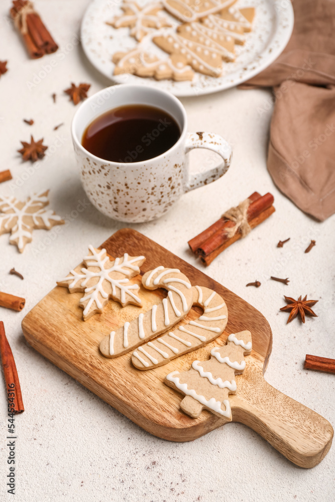 浅色背景下有美味的圣诞饼干、一杯咖啡和香料的木板